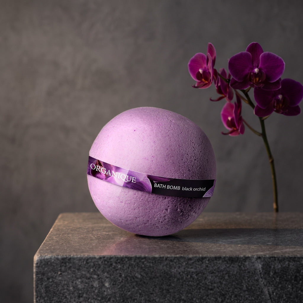 Bath Bomb – Black Orchid on a dark stone vanity with purple orchids