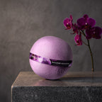 Bath Bomb – Black Orchid on a dark stone vanity with purple orchids