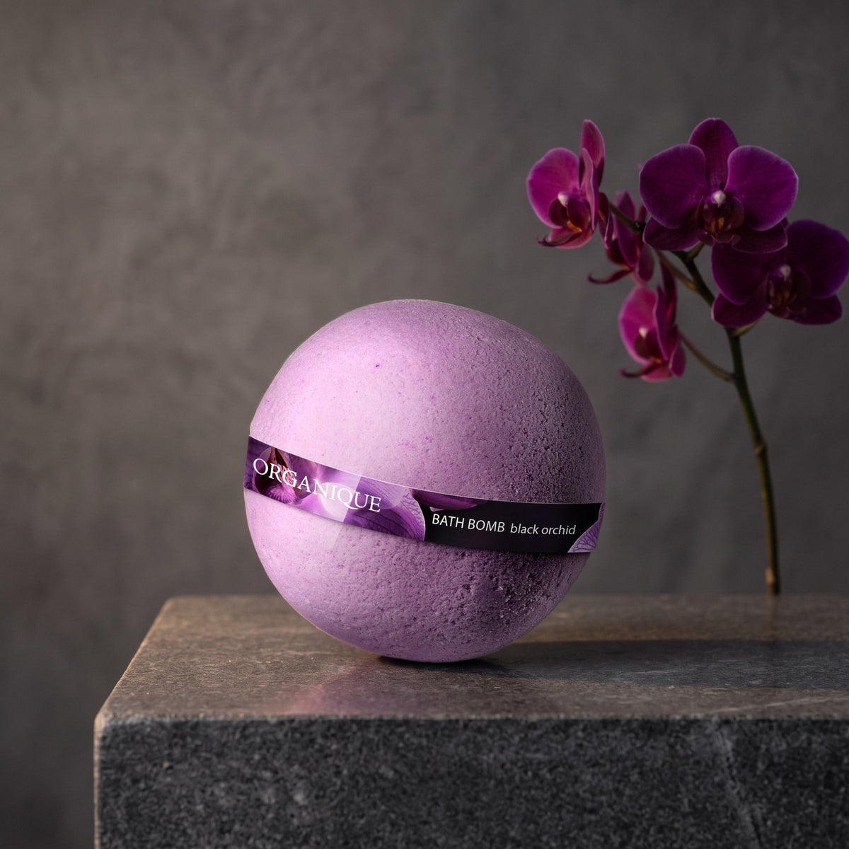Bath Bomb – Black Orchid on a dark stone vanity with purple orchids
