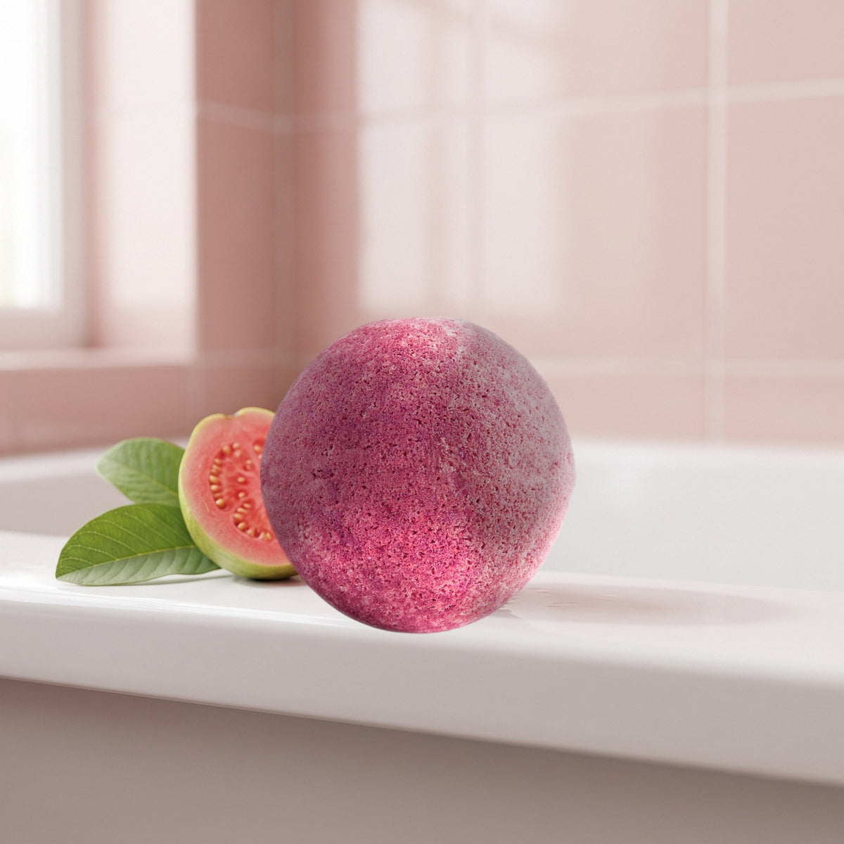 Bath Bomb – Guava on the rim of a bathtub with a pink guava