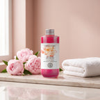 Bloom Essence Bath Foam 200 ml on a marble ledge with pink peonies and a white towel