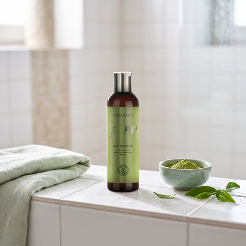 Feel Up Shampoo 250 ml on a tiled shower ledge with green tea leaves and matcha