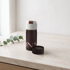 Hunn Face Towel – Coconut White on a travertine bathroom vanity with a sprig of eucalyptus