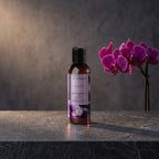 Bath & Massage Oil – Black Orchid 125 ml on a dark stone vanity with purple orchids