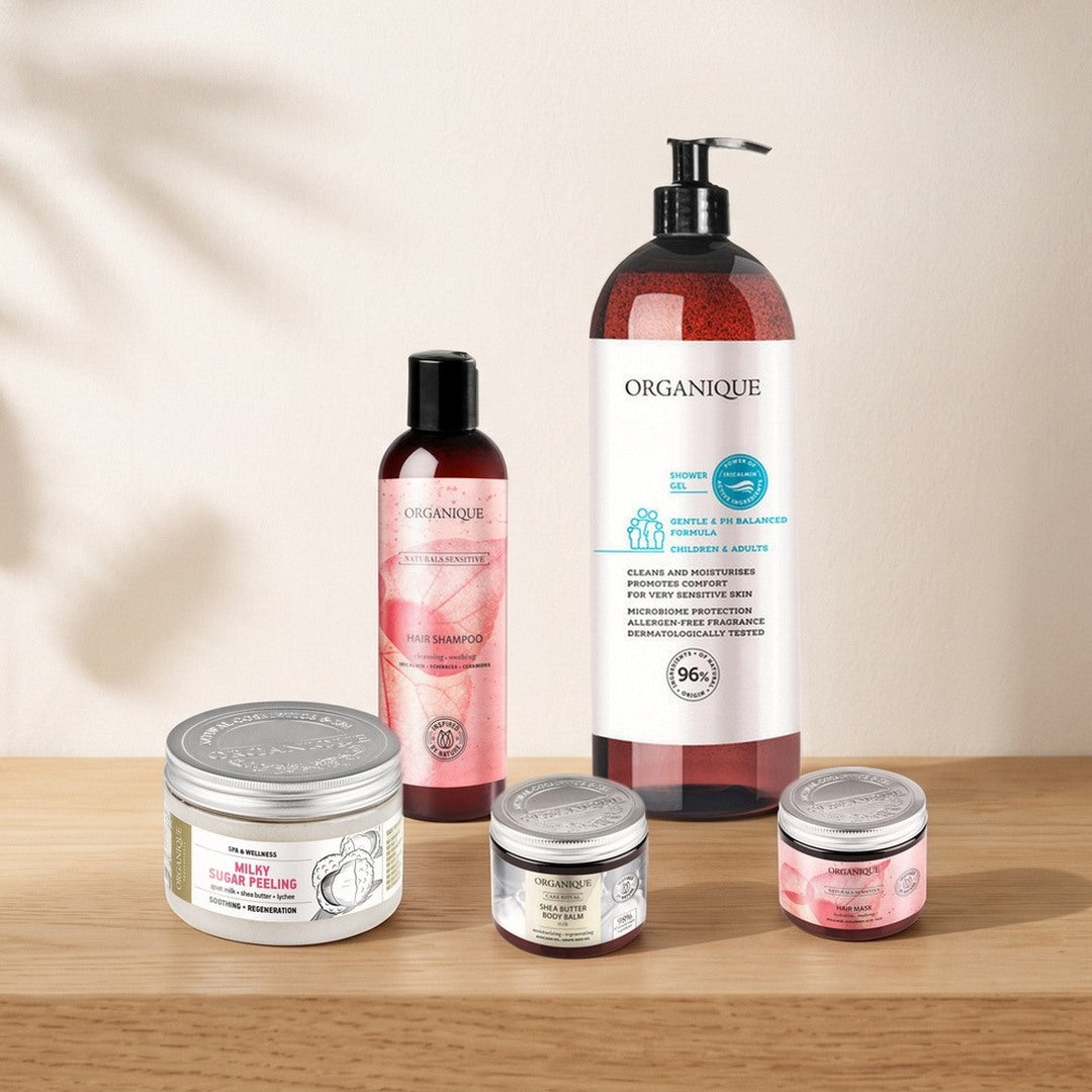 Organique best sellers on a sunlit oak shelf: family shower gel, sensitive shampoo and hair mask, milk sugar scrub and shea butter body balm