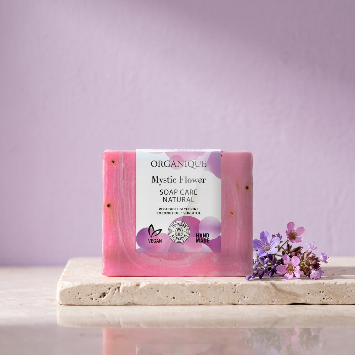 Natural Soap Cube – Mystic Flower 100 g on a stone ledge with violet flowers