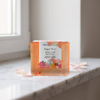 Natural Soap Cube – Sugar Rose 100 g on a white marble ledge with rose petals