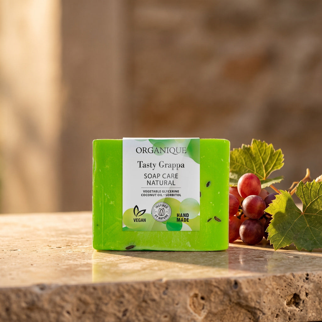 Natural Soap Cube – Tasty Grappa 100 g on a stone ledge with red grapes and vine leaves