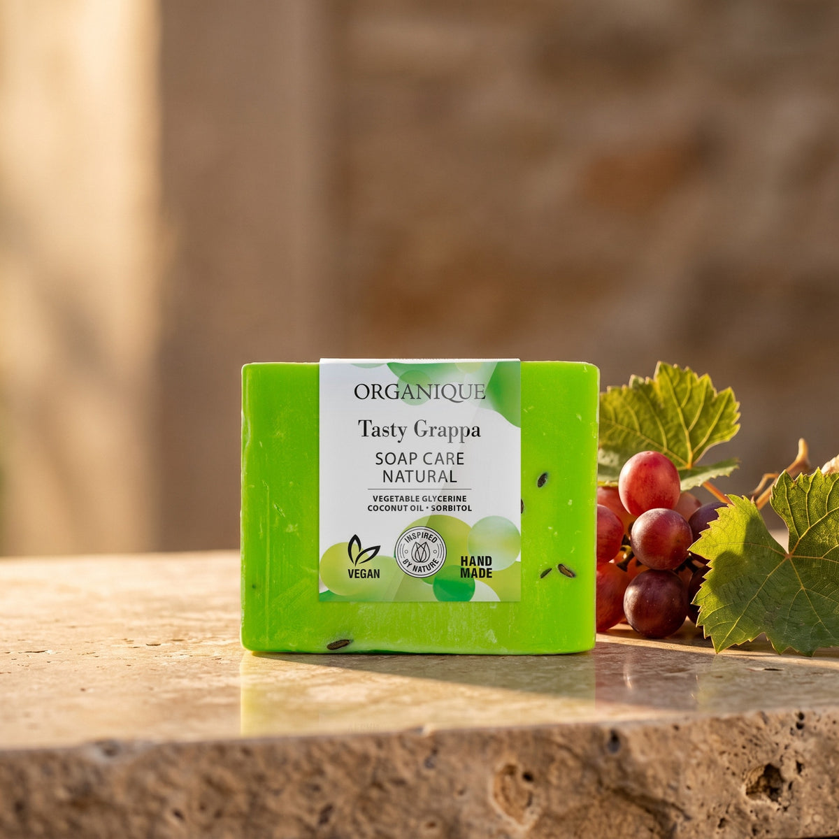 Natural Soap Cube – Tasty Grappa 100 g on a stone ledge with red grapes and vine leaves